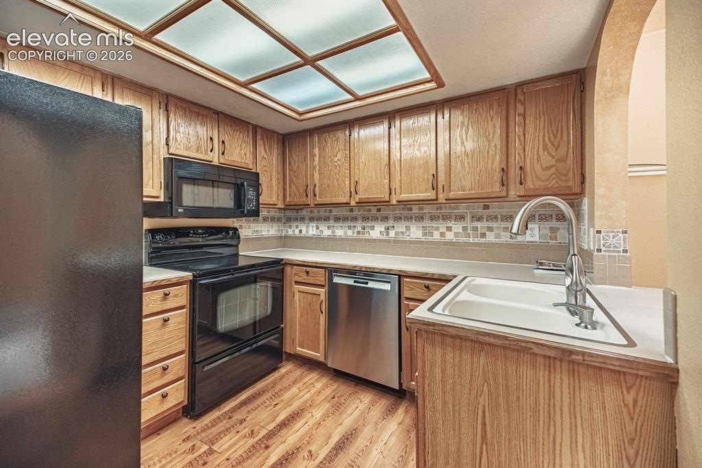 Image 8 of 36: Kitchen featuring wood-finish cabinetry, an inset double basin sink with a