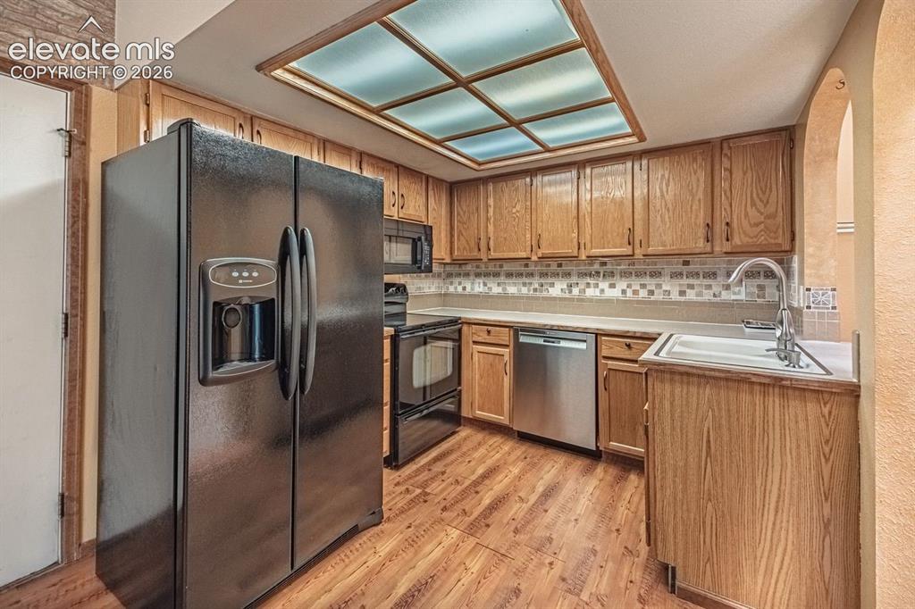 Image 9 of 36: Kitchen featuring wood-finish flooring, oak cabinetry, and a textured backs