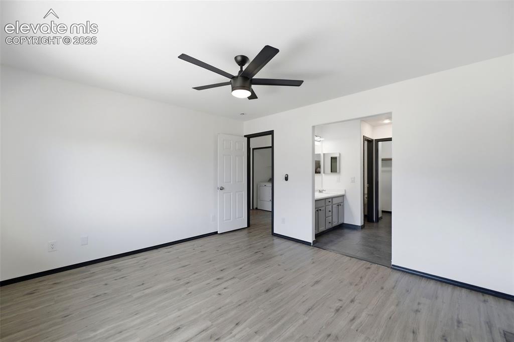 Image 16 of 48: Spacious room featuring wood-finish flooring, white walls, and a contempora
