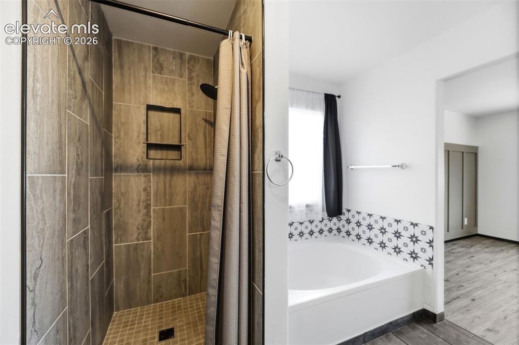 Image 19 of 48: Bathroom featuring a tiled shower with a built-in niche, a white soaking tu