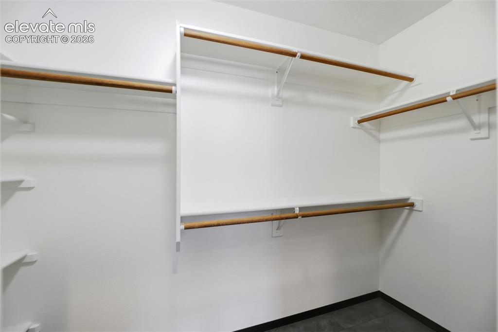 Image 20 of 48: Walk-in closet with white walls, multiple built-in shelving units, and natu