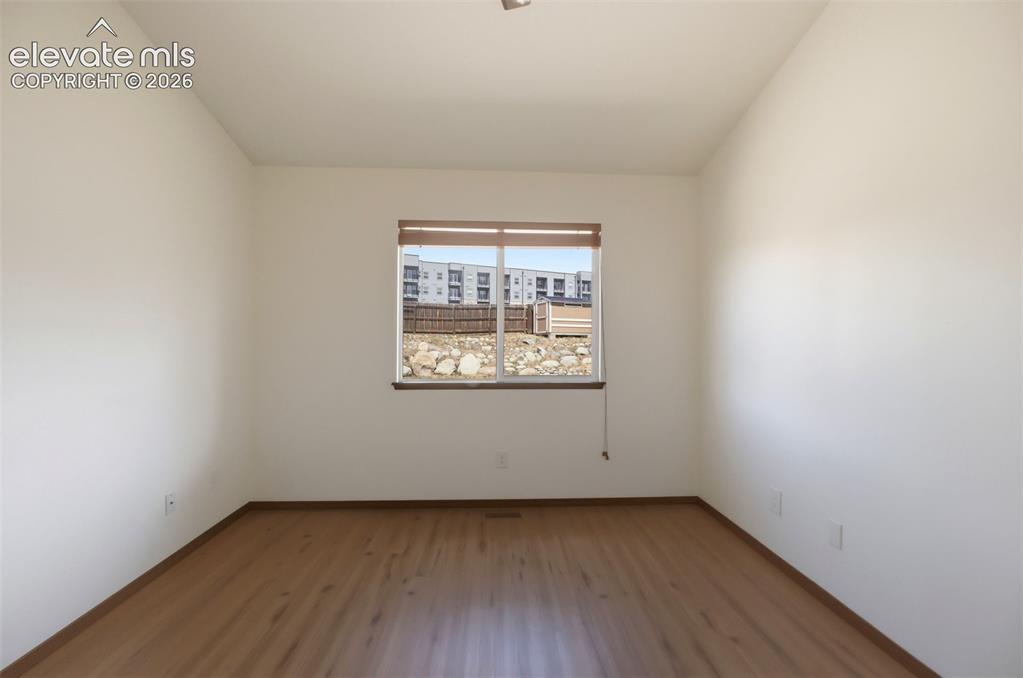 Image 22 of 48: Room featuring wood-finish flooring, a single window with blinds, and white