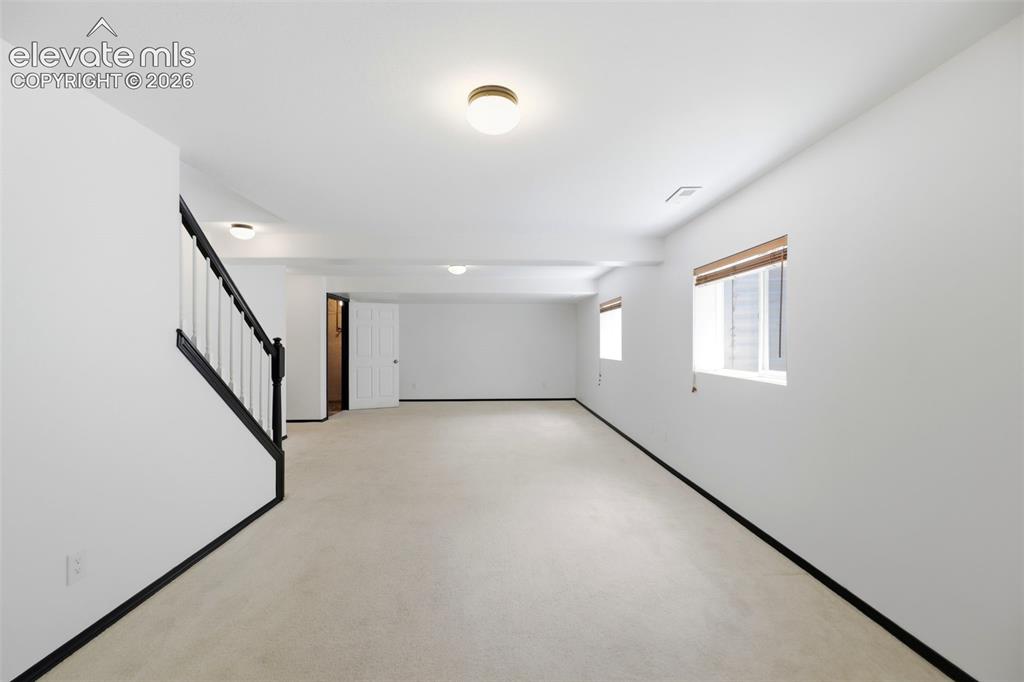 Image 27 of 48: Spacious lower-level room featuring light-toned carpet, white walls, and re