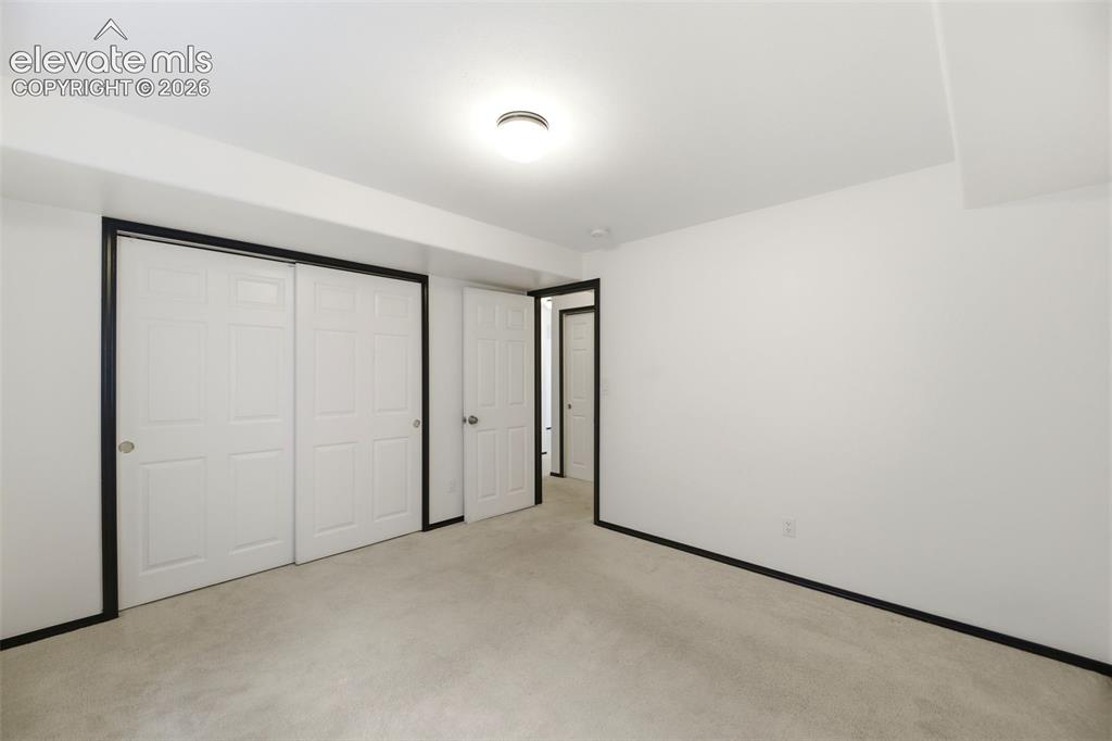 Image 30 of 48: Carpeted room with white walls, contrasting black trim, and a flush-mount c