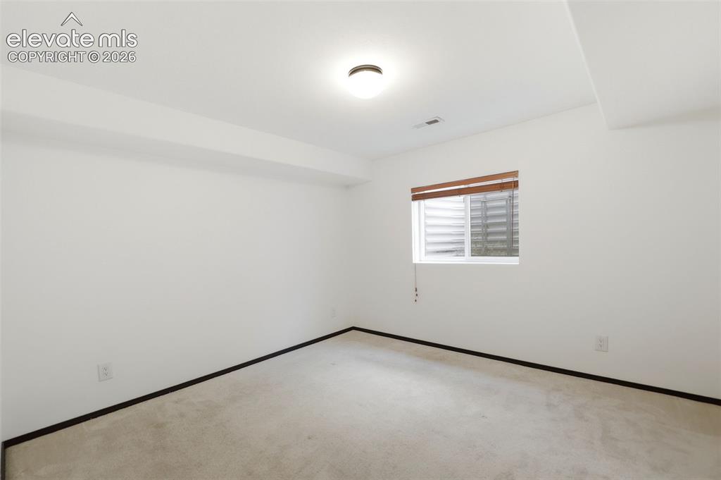 Image 31 of 48: Carpeted room with a single window featuring wood-finish blinds
