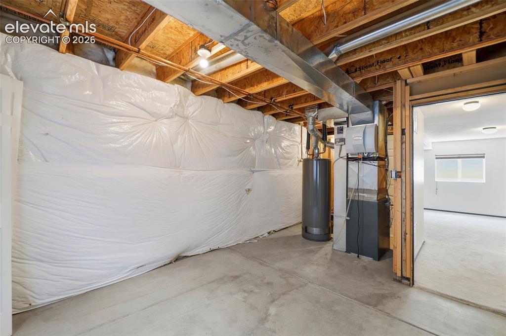 Image 32 of 48: Unfinished basement space featuring exposed wood joists and concrete floori