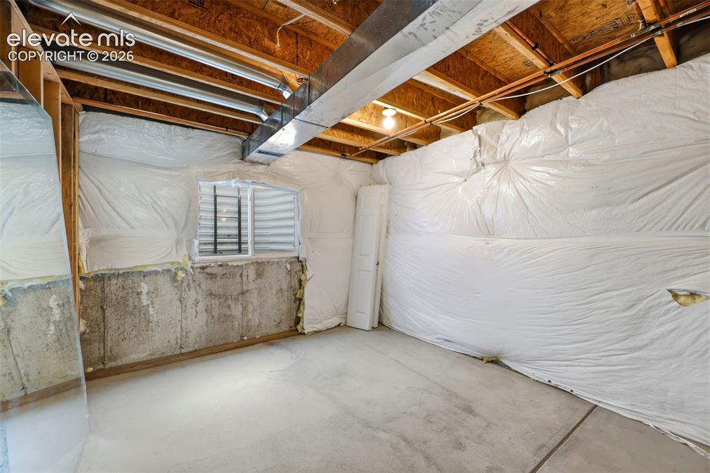 Image 33 of 48: Unfinished basement space featuring exposed wood joists, concrete flooring,