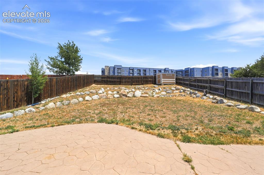 Image 36 of 48: Fenced backyard featuring a stamped concrete patio, rock garden elements, a