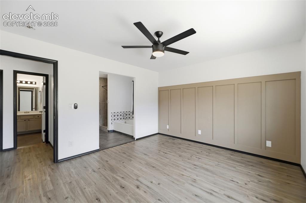 Image 4 of 48: Room featuring wood-finish flooring, a wall with decorative paneling, and a
