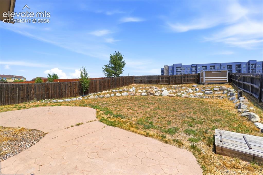 Image 43 of 48: Expansive backyard featuring a stamped concrete patio, wood privacy fencing