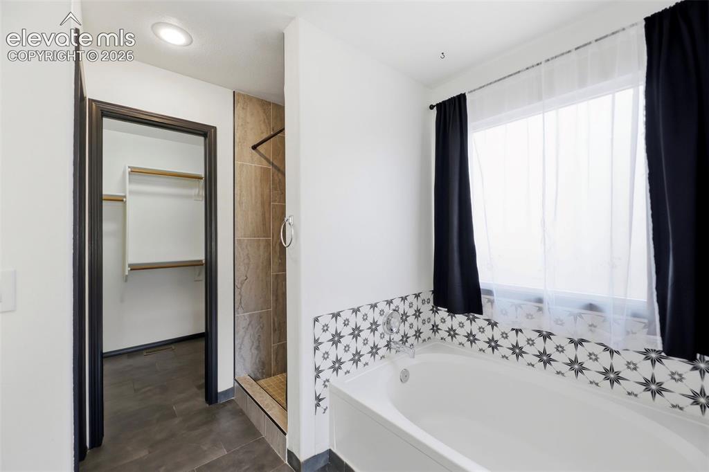Image 5 of 48: Freestanding soaking tub with decorative tile surround and privacy window