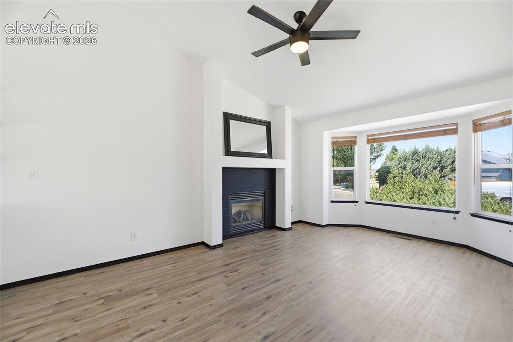 Image 7 of 48: Living area with wood-finish flooring, a contemporary ceiling fan, and a ga