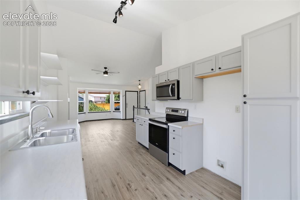 Image 9 of 48: Kitchen featuring light wood-finish flooring, white cabinetry, light counte