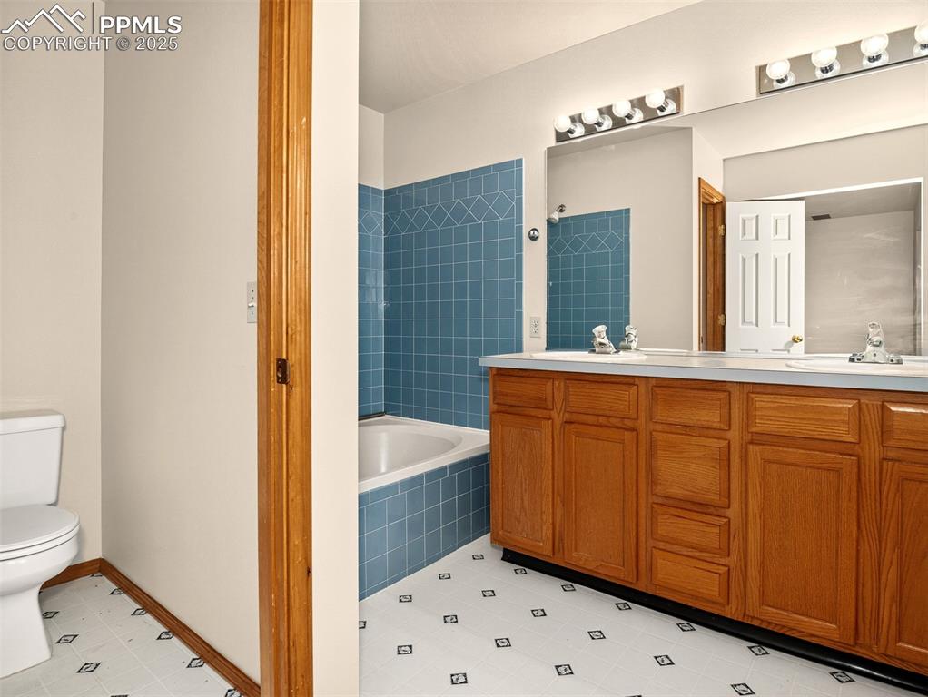 Image 16 of 26: Bathroom with double vanity and tiled shower / bath