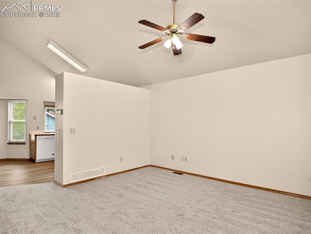 Image 3 of 26: Empty room with carpet, ceiling fan, and high vaulted ceiling