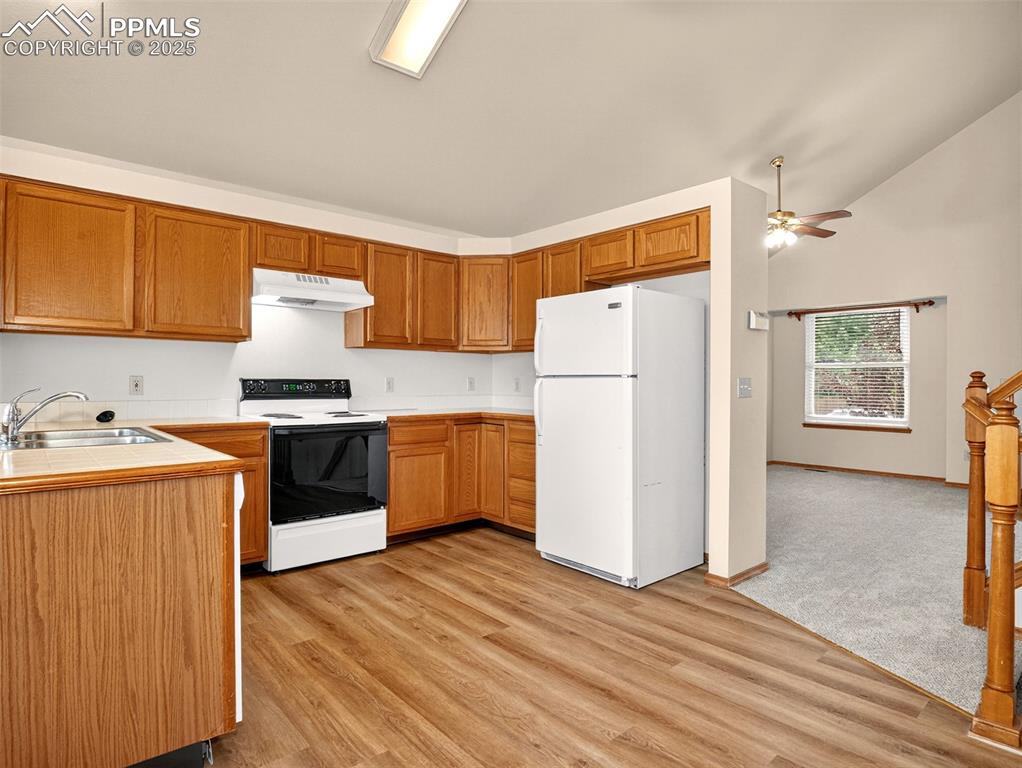 Image 6 of 26: Kitchen with white appliances, under cabinet range hood, brown cabinets, lo