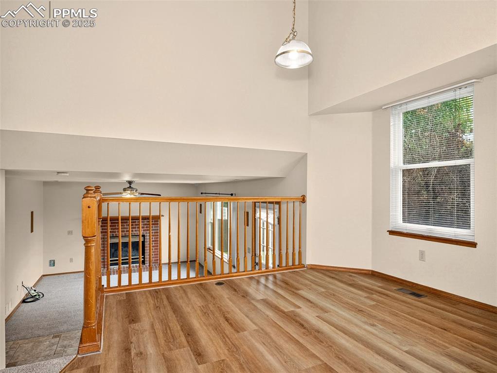 Image 8 of 26: Unfurnished room featuring a towering ceiling, light wood-type flooring, a