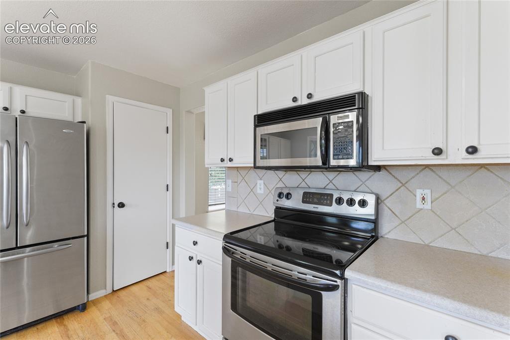 Image 11 of 36: Kitchen featuring white cabinetry with dark hardware, stainless steel appli