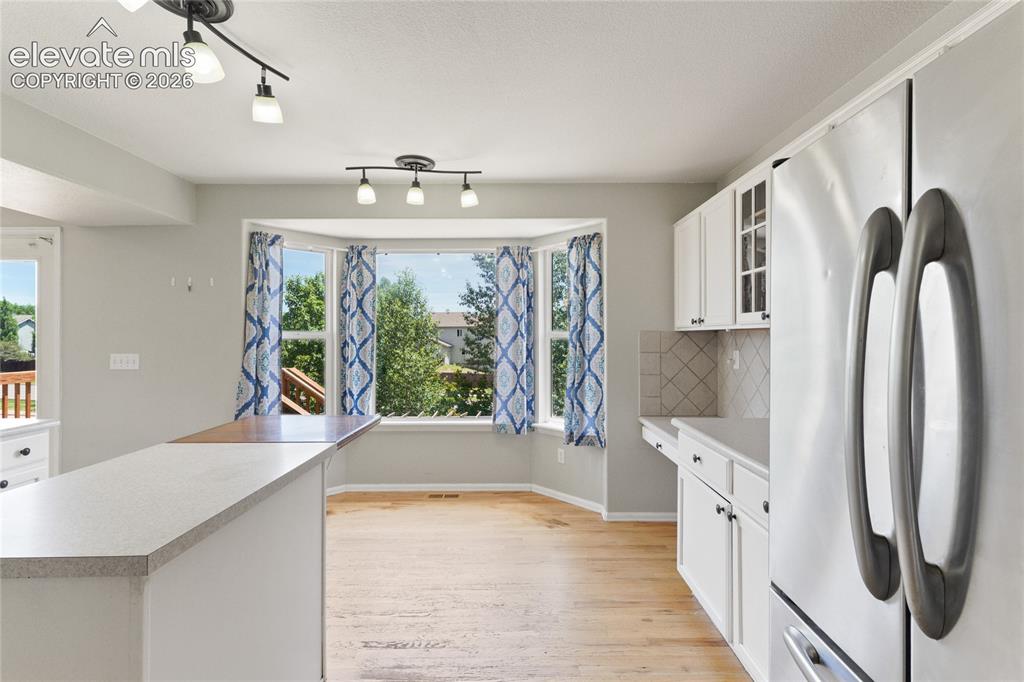 Image 12 of 36: Kitchen featuring a bay window, white cabinetry with dark hardware, a light