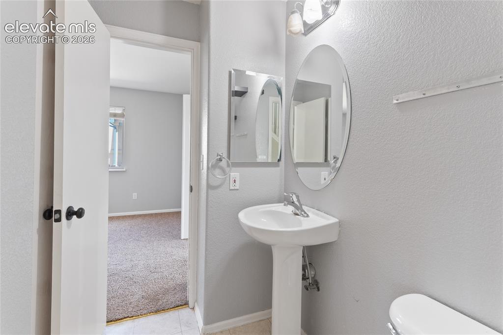 Image 15 of 36: Pedestal sink with chrome faucet, oval mirror, and wall-mounted light fixtu