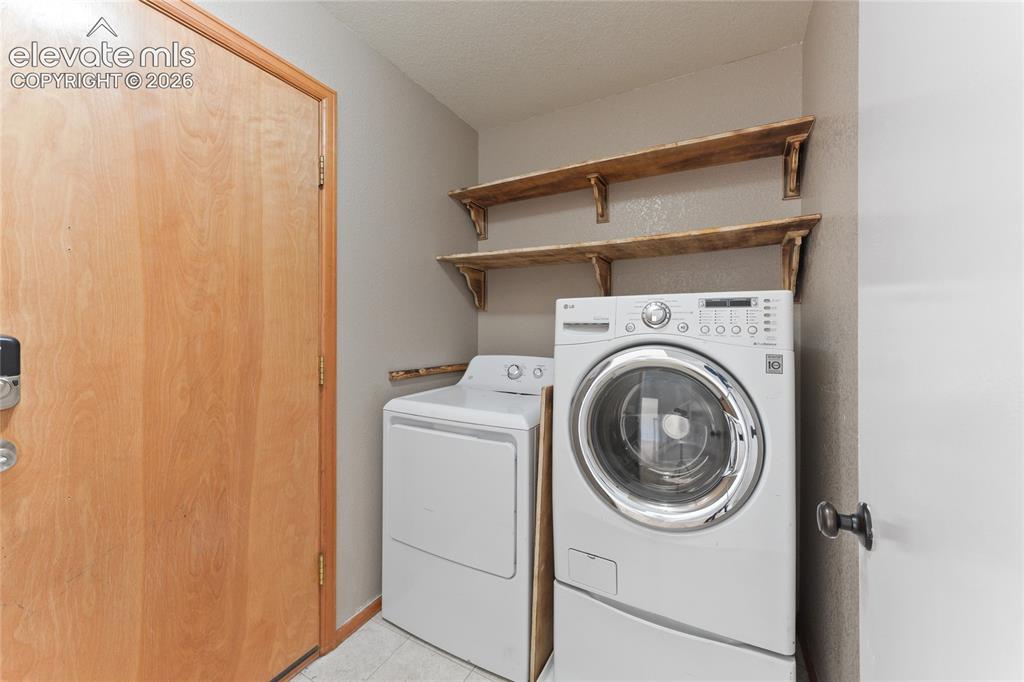 Image 16 of 36: Dedicated laundry space featuring a light wood-finish door, wood-finish ope