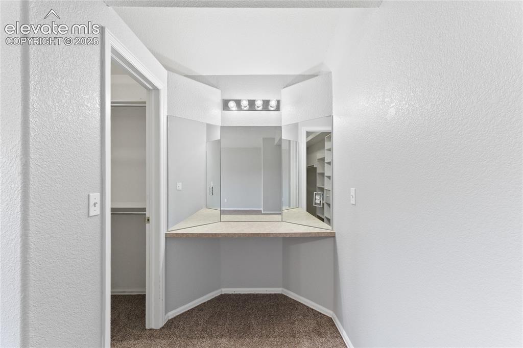 Image 22 of 36: Built-in vanity with tri-fold mirror, integrated lighting, and neutral coun