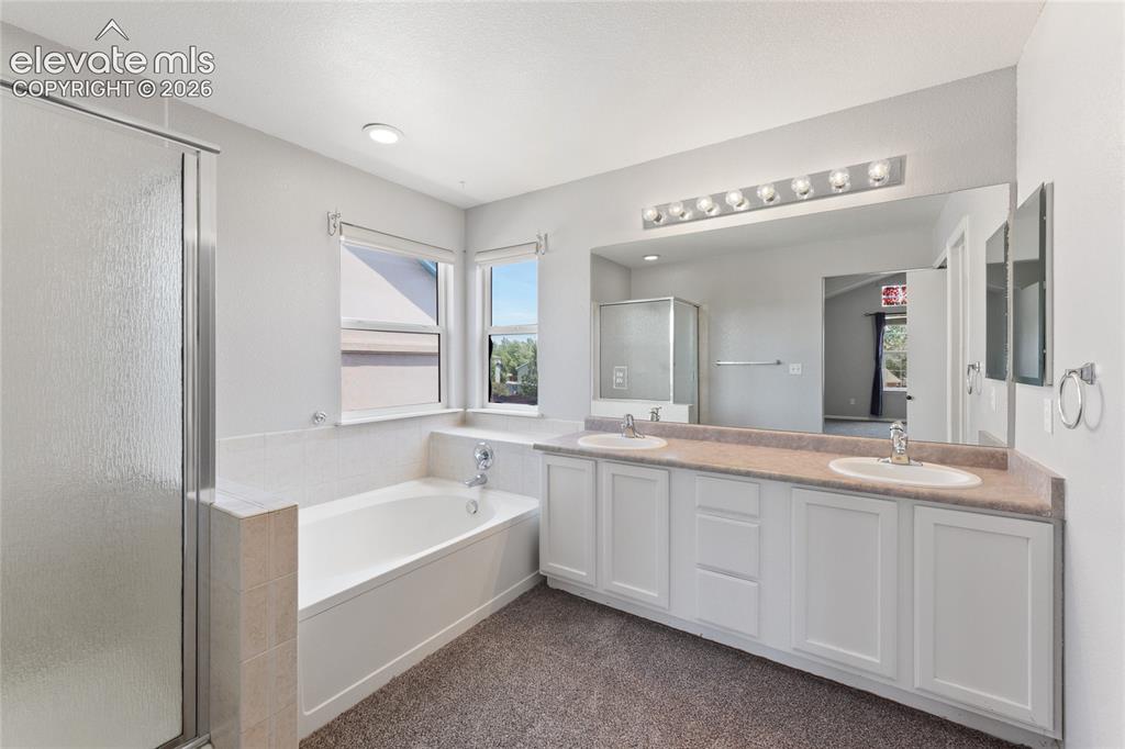 Image 23 of 36: Dual vanity with white cabinetry, integrated sinks, and a large mirror