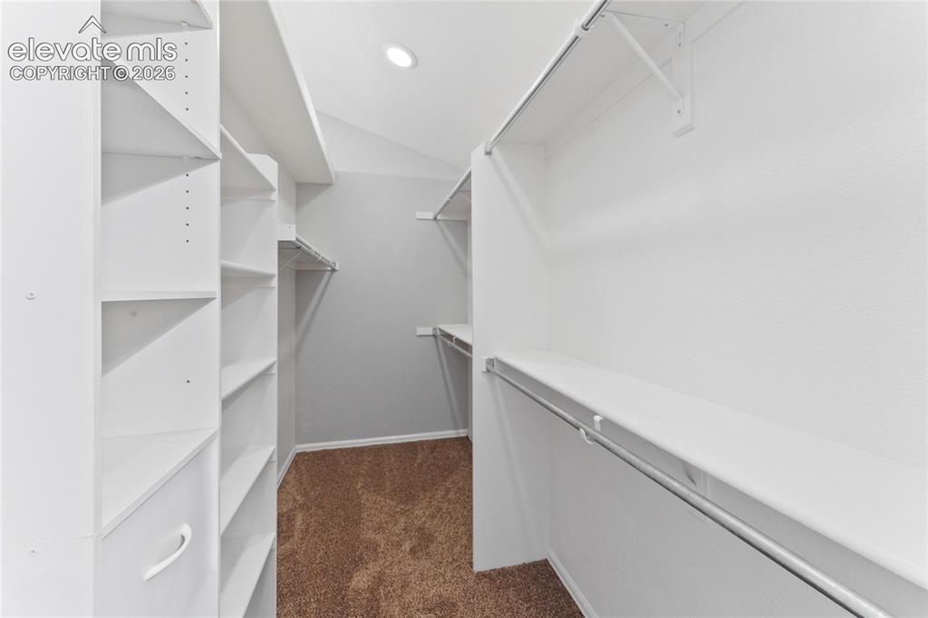Image 25 of 36: Walk-in closet featuring extensive built-in shelving, multiple hanging rods