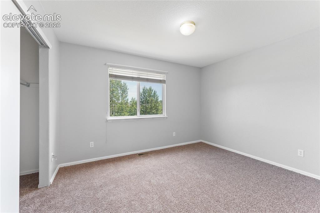 Image 29 of 36: Carpeted room with a window providing natural light, featuring a ceiling-mo
