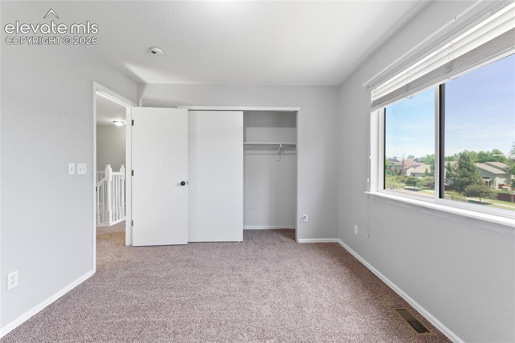 Image 30 of 36: Bright bedroom featuring neutral-toned carpeting and light gray walls