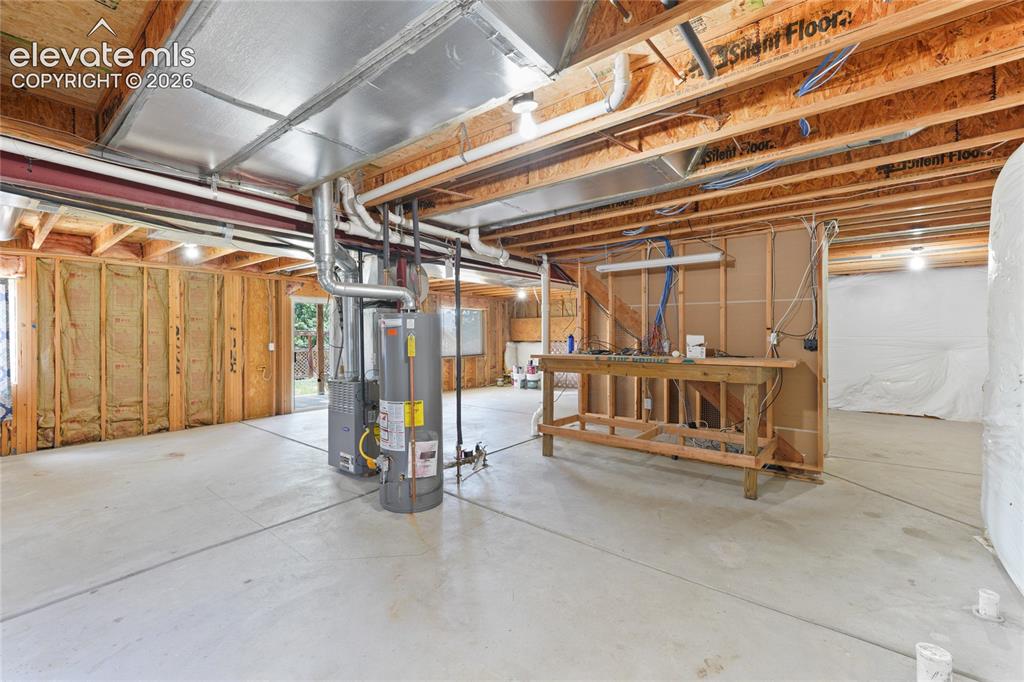 Image 31 of 36: Unfinished basement featuring concrete flooring, exposed wood joists, and a