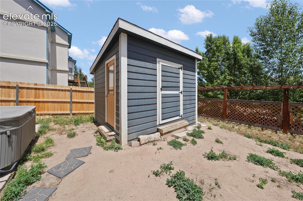 Image 35 of 36: Detached storage shed with horizontal siding, a light wood door, and a whit