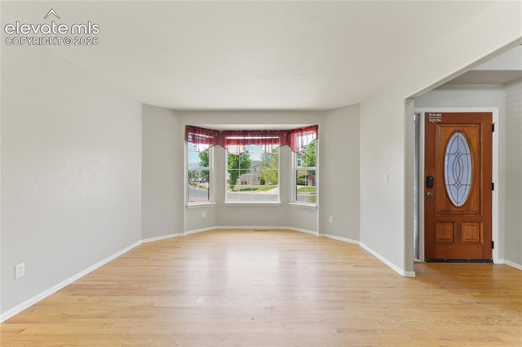 Image 4 of 36: Bay window with white trim, wood-finish flooring, and light gray walls