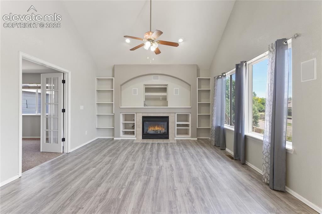 Image 6 of 36: Spacious living area featuring vaulted ceilings, wood-finish flooring, and 
