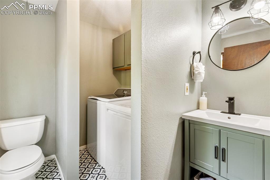 Image 19 of 50: Main level Bathroom featuring vanity, washing machine and dryer, and a text