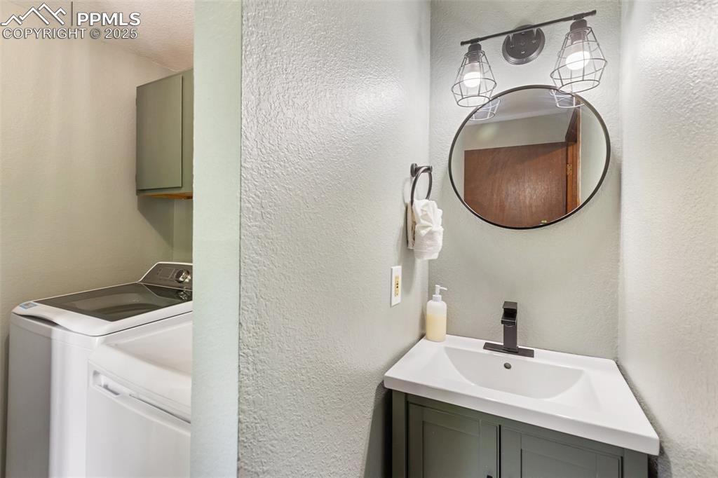 Image 20 of 50: Main level Bathroom featuring vanity, a textured wall, and washer and cloth