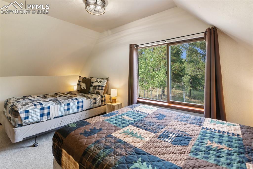 Image 30 of 50: Upper level Carpeted bedroom featuring vaulted ceiling and multiple windows