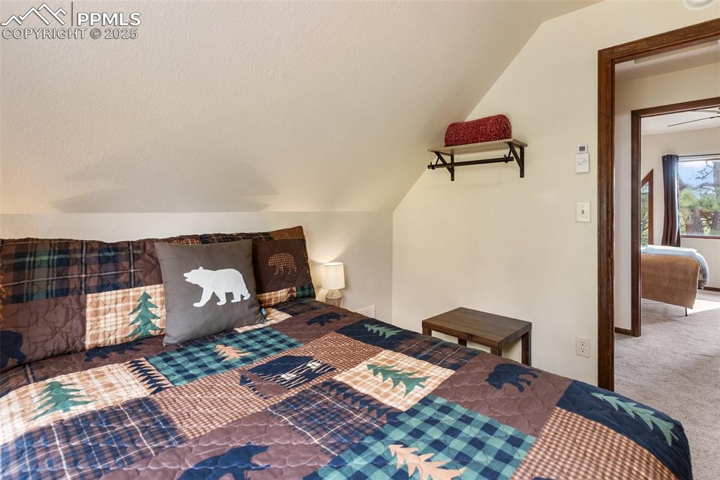Image 31 of 50: Upper level Bedroom featuring lofted ceiling and carpet