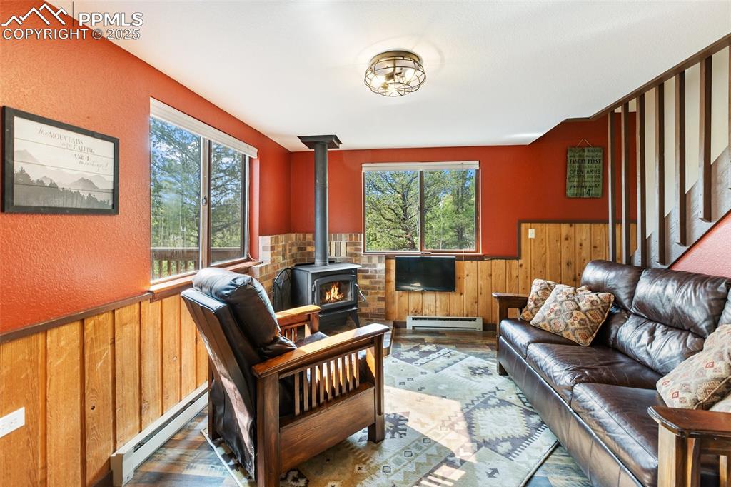 Image 8 of 50: Living room


room featuring a wainscoted wall, a wood stove, wooden wal