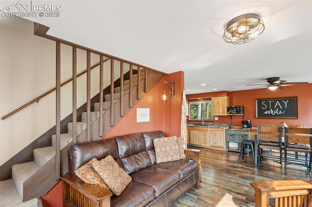 Image 9 of 50: Living room with stairs, dark wood-style flooring, recessed lighting, and c
