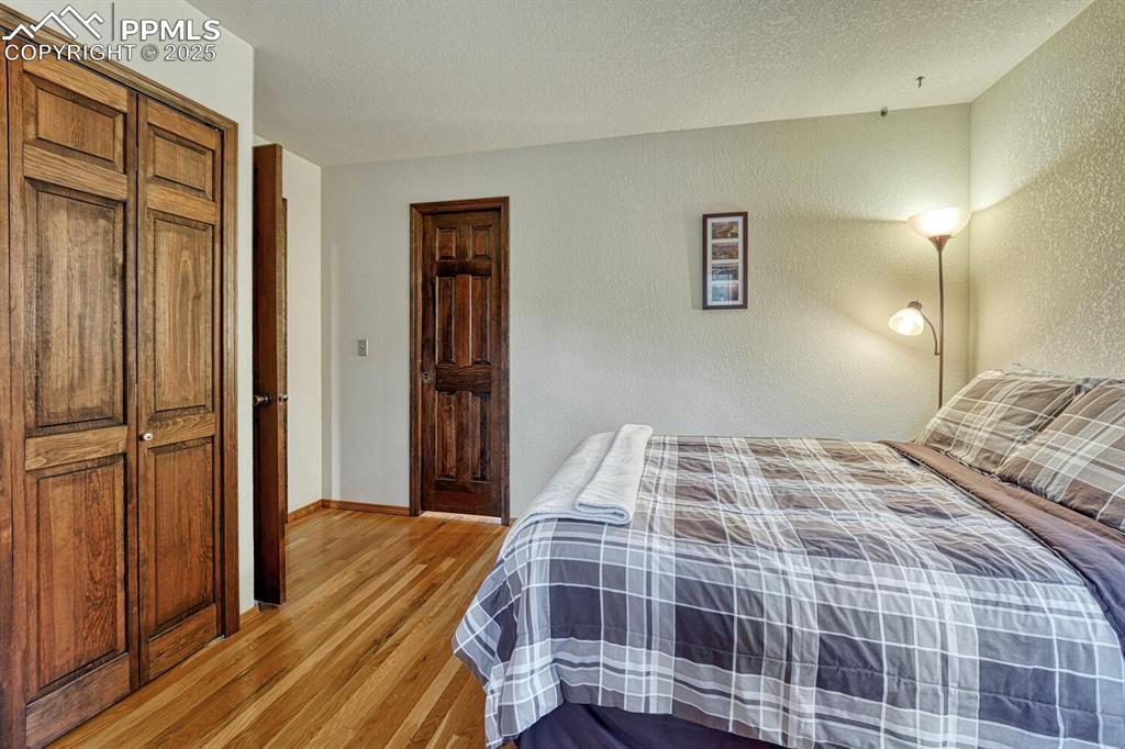Image 26 of 50: Bedroom featuring light wood-type flooring, a textured wall, baseboards, an