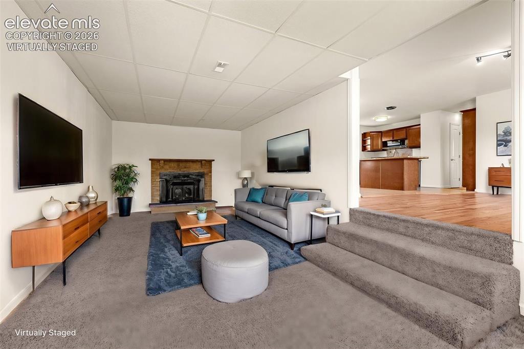 Image 9 of 43: Virtually Staged main level living room with wood burning fireplace