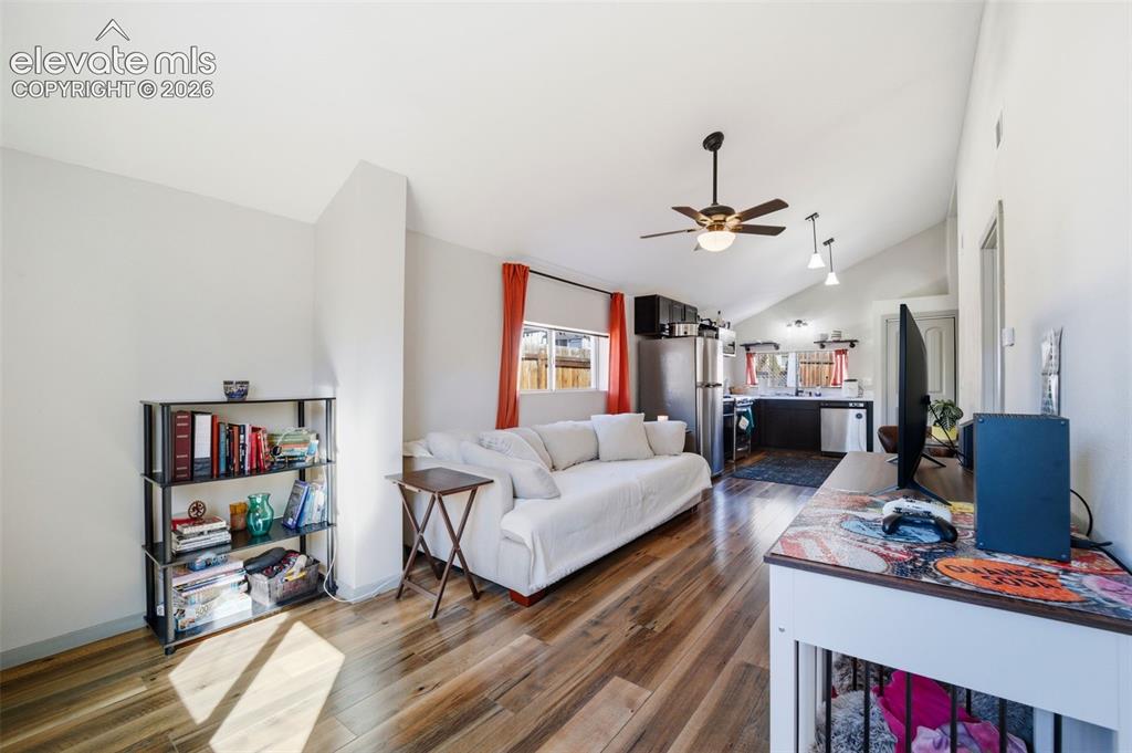 Image 14 of 30: Open-concept living area featuring vaulted ceilings, wood-finish flooring,