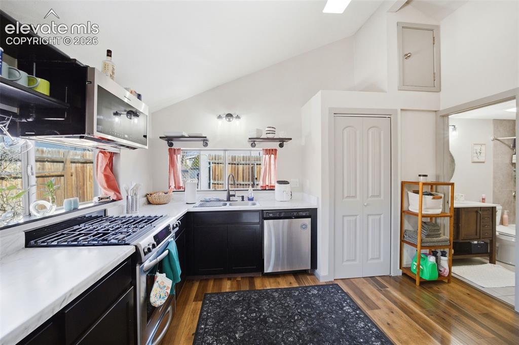 Image 18 of 30: Kitchen featuring dark cabinetry, stainless steel appliances, wood-finish f