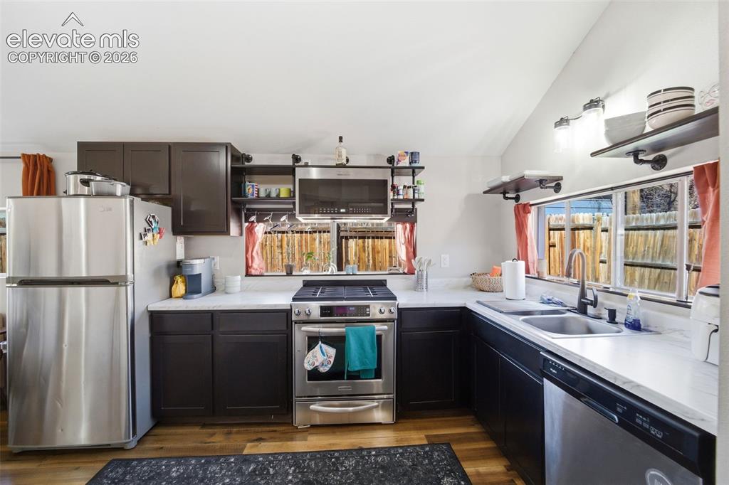 Image 19 of 30: Kitchen featuring wood-finish flooring, dark cabinetry, light-toned counter