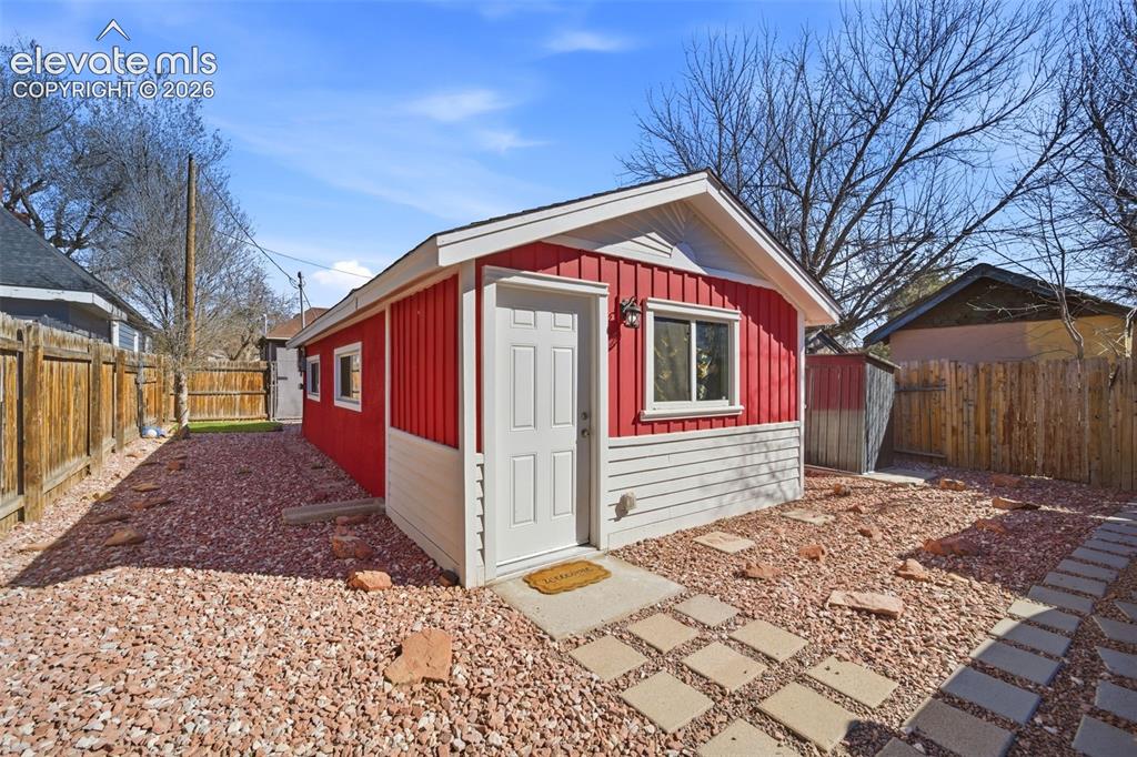 Image 28 of 30: Single-story residence featuring a chain-link fence, concrete pathway, and