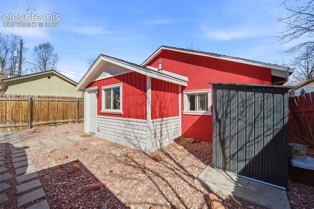 Image 29 of 30: Red exterior structure featuring white trim and a white entry door