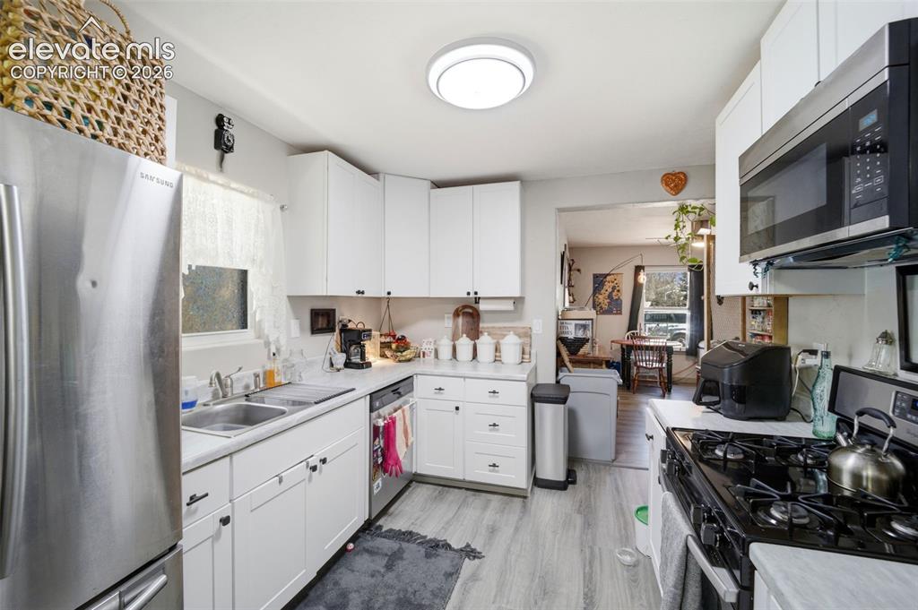 Image 5 of 30: Open-concept living area with wood-finish flooring, a ceiling fan, and an i