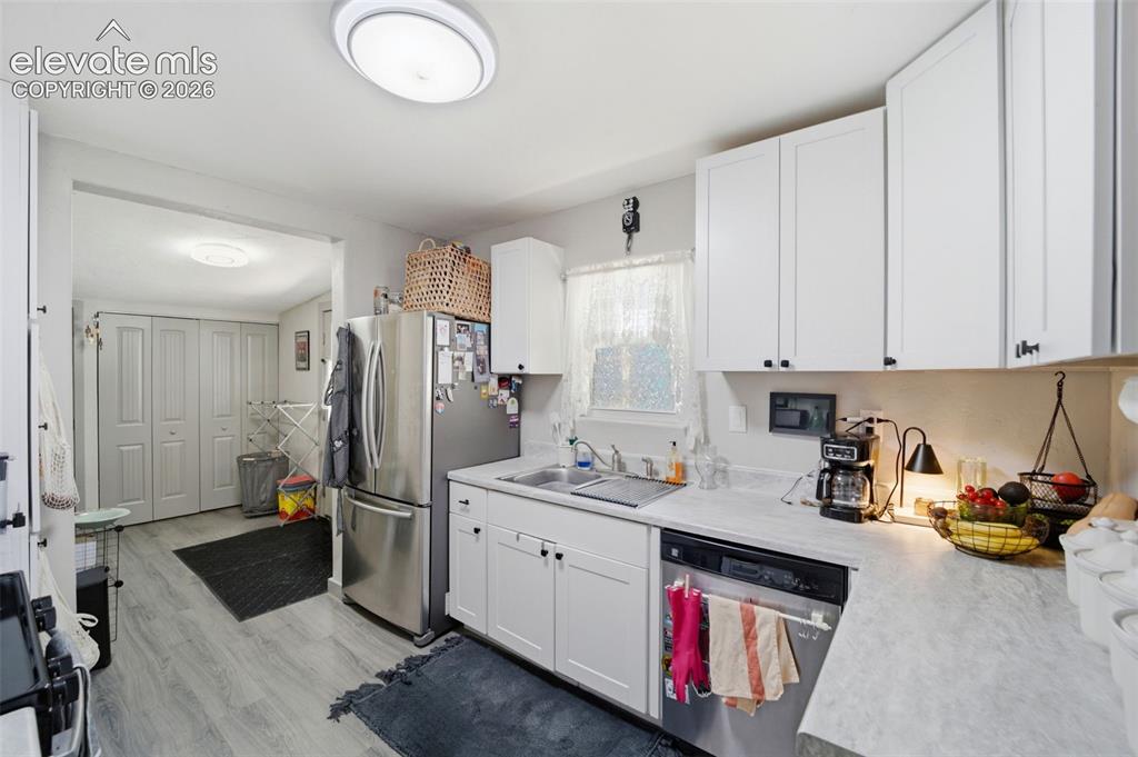 Image 6 of 30: Kitchen featuring white cabinetry, light-toned countertops, and wood-finish