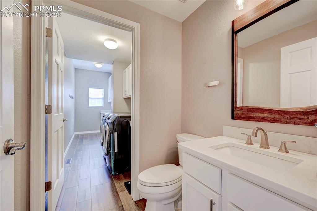 Image 15 of 31: Bathroom with separate washer and dryer, toilet, vanity, and wood finished 